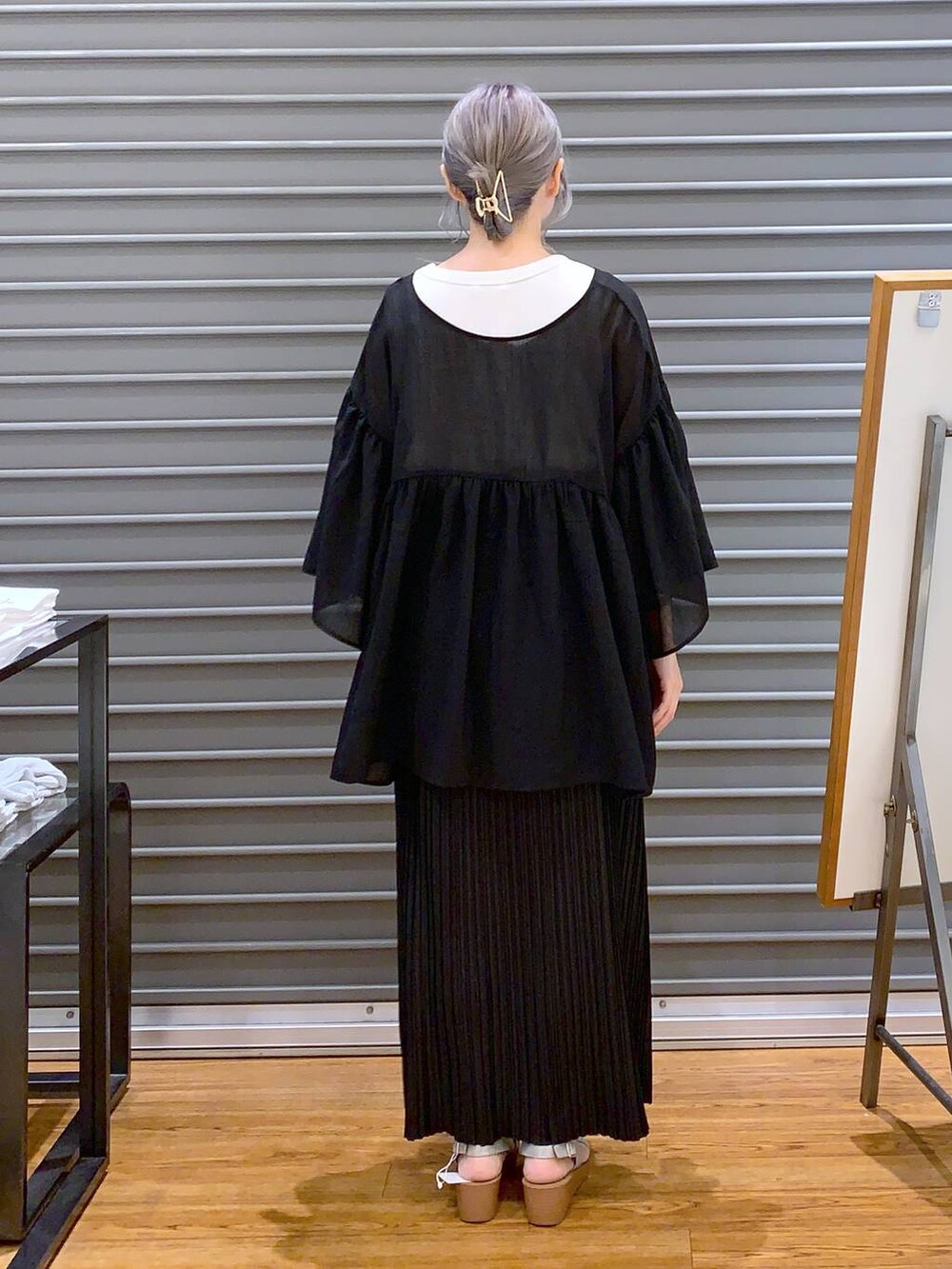 ブラック系のスカート、ブラック系のハンドバッグ、シルバー系のサンダルを着用したレディースの夏コーディネートの2枚目の写真