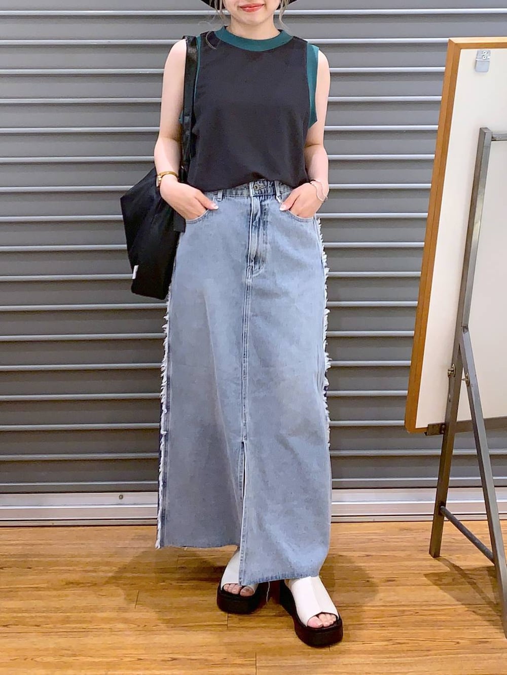 グレー系のタンクトップ、ホワイト系のサンダル、ブラック系のショルダーバッグを着用したレディースの夏コーディネートの4枚目の写真