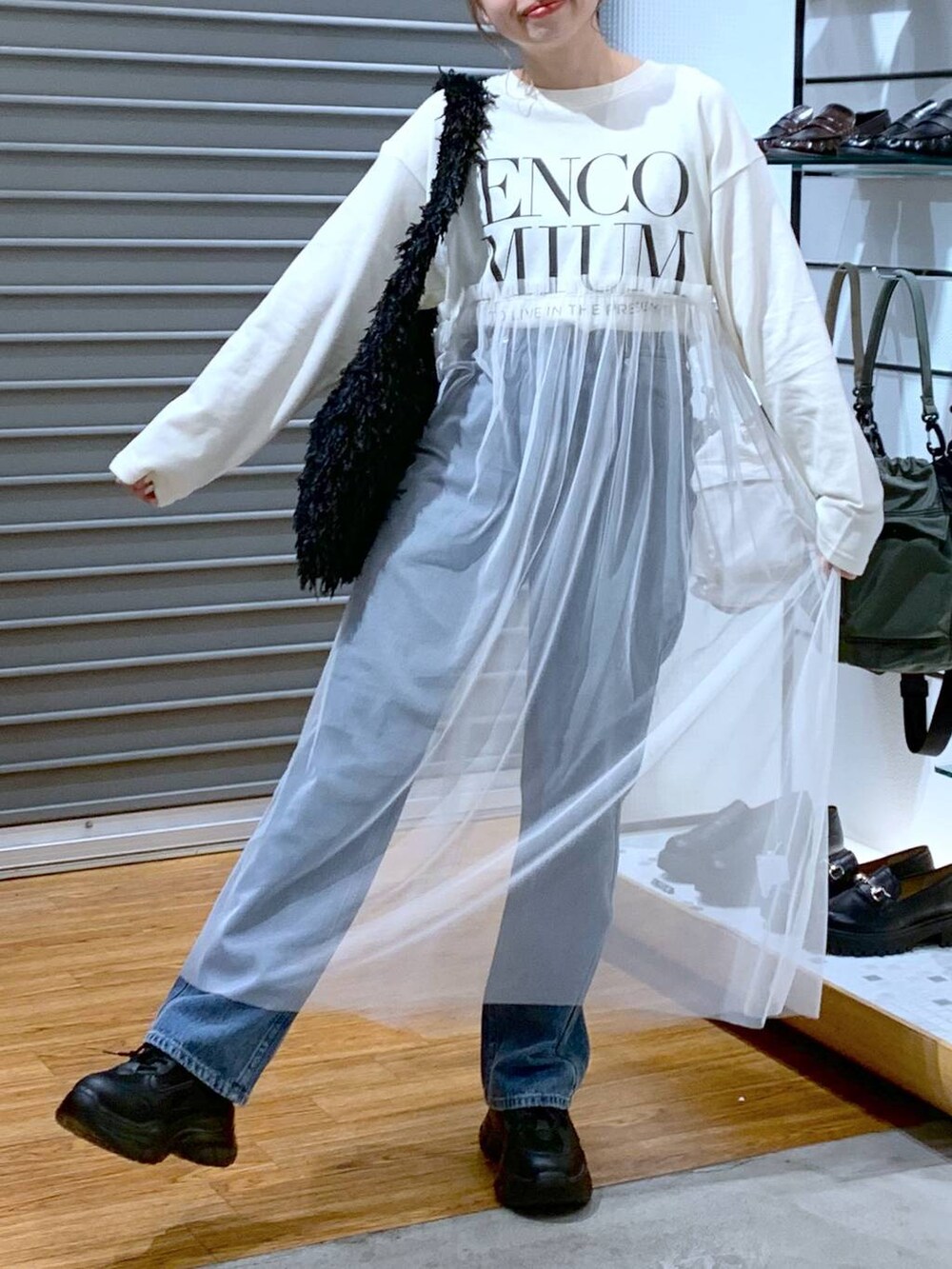 ブラック系のスニーカー、ブルー系のデニムパンツ、ブラック系のショルダーバッグを着用したレディースの秋コーディネートの6枚目の写真