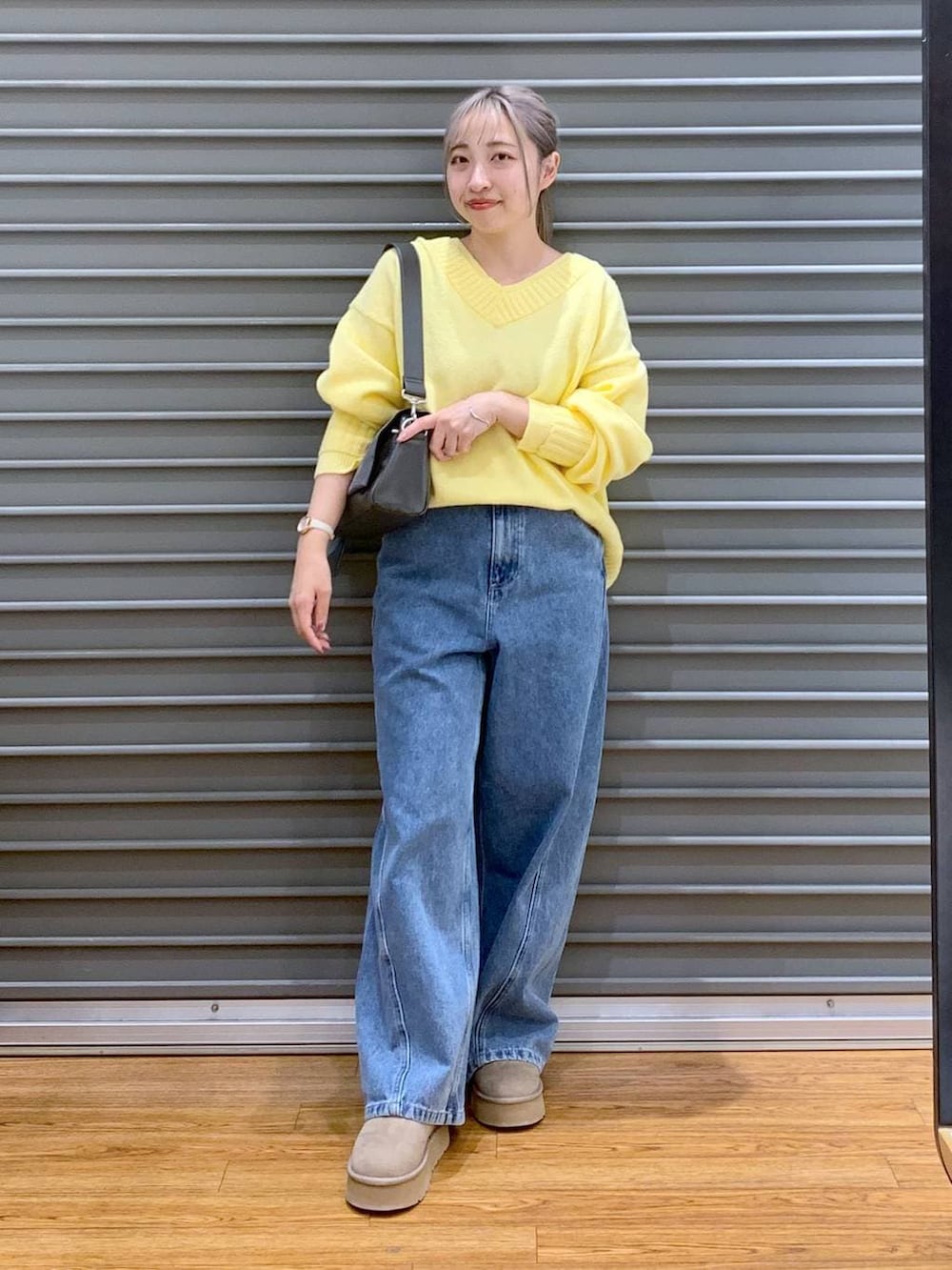 グレー系のショルダーバッグ、イエロー系のニット/セーター、ブルー系のデニムパンツを着用したレディースの冬コーディネートの5枚目の写真