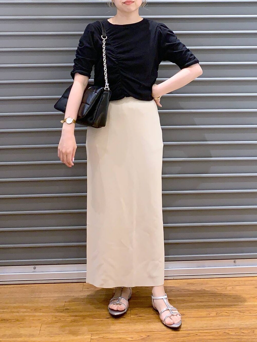 ブラック系のショルダーバッグ、ベージュ系のスカート、シルバー系のサンダルを着用したレディースの春コーディネートの7枚目の写真