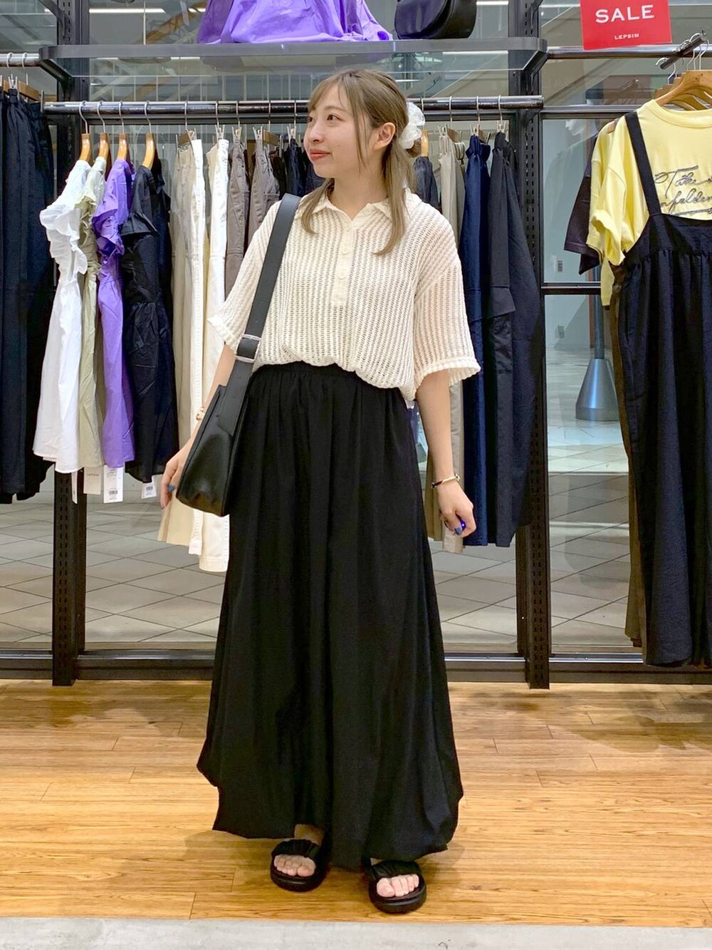 ブラック系のサンダル、ブラック系のスカート、ホワイト系のポロシャツを着用したレディースの夏コーディネートの4枚目の写真