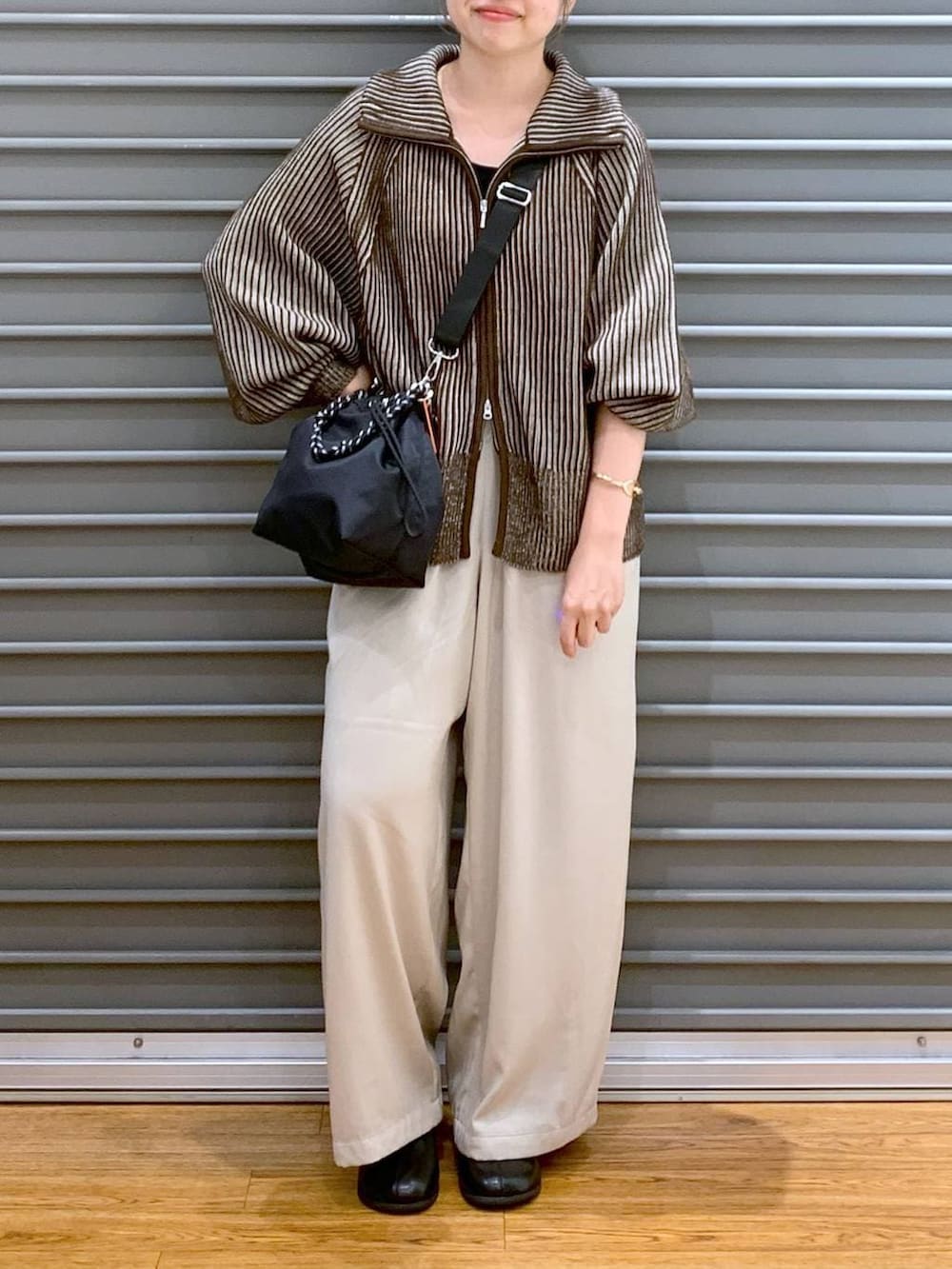 ブラック系のショルダーバッグ、ブラウン系のカーディガン/ボレロ、ブラック系のブーツを着用したレディースの冬コーディネートの4枚目の写真