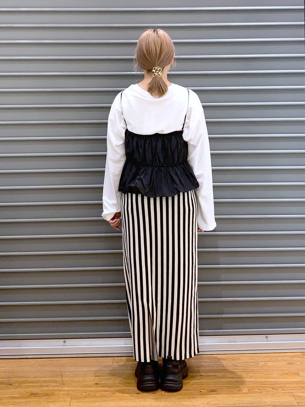 ブラック系のショルダーバッグ、ブラック系のスニーカー、ホワイト系のスカートを着用したレディースの春コーディネートの2枚目の写真