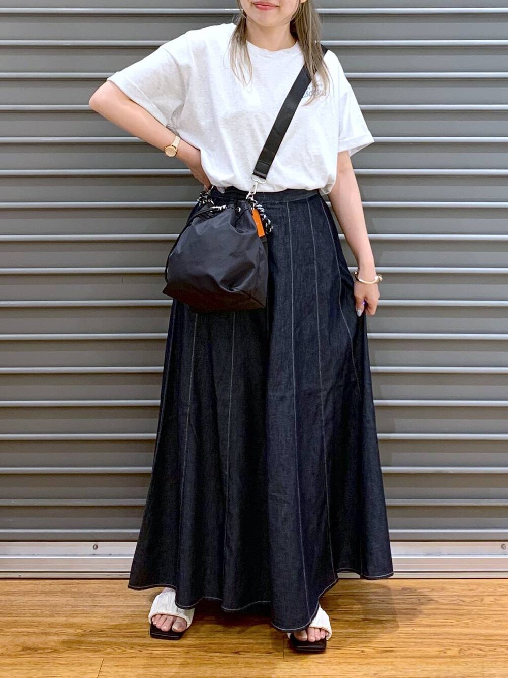 ブルー系のスカート、ホワイト系のサンダル、ブラック系のショルダーバッグを着用したレディースの夏コーディネートの7枚目の写真