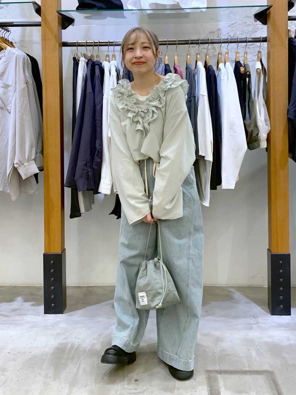 グリーン系のショルダーバッグ、ブルー系のデニムパンツ、ブラック系のサンダルを着用したレディースの春コーディネートの5枚目の写真