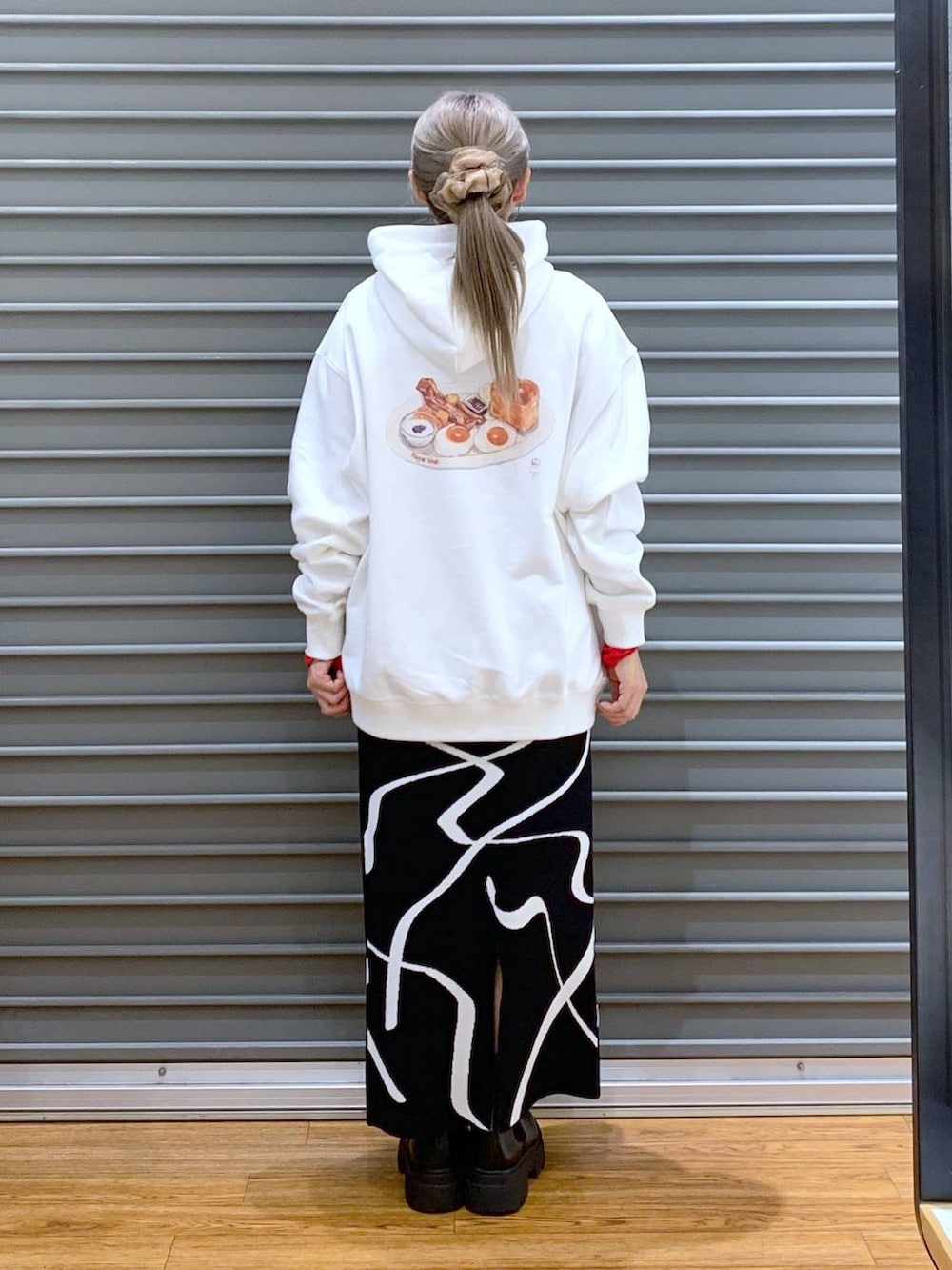 ブラック系のスカート、ブラック系のショルダーバッグ、ブラック系のブーツを着用したレディースの冬コーディネートの2枚目の写真