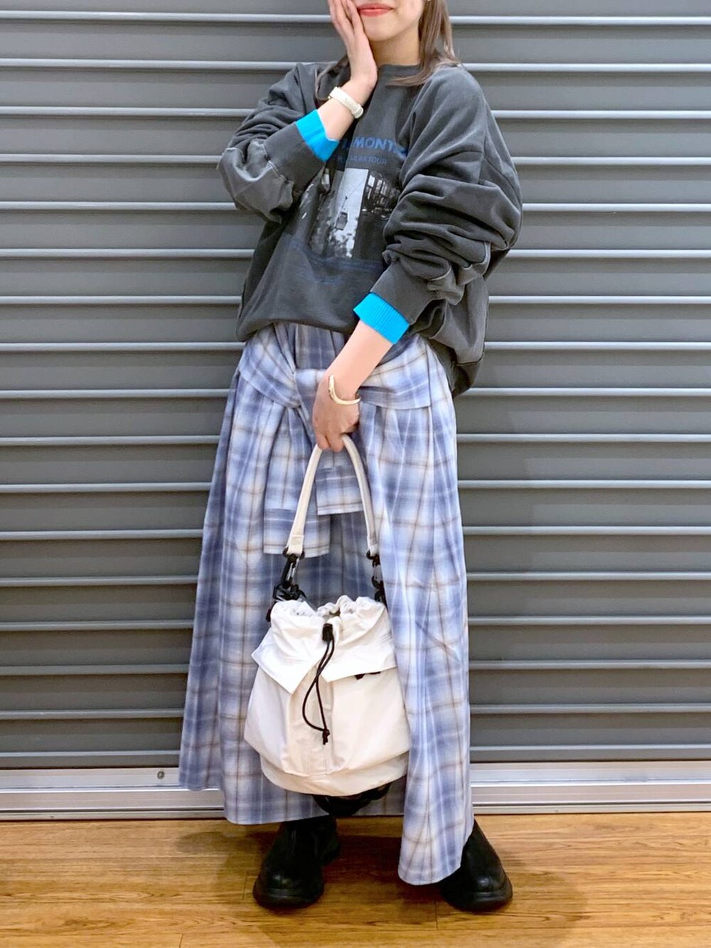 ホワイト系のショルダーバッグ、ブラック系のブーツ、ブルー系のスカートを着用したレディースの春コーディネートの5枚目の写真