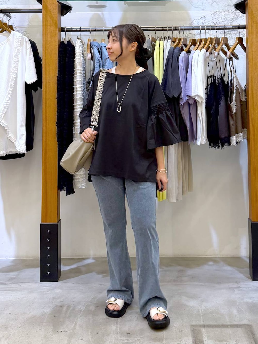 ブラック系のTシャツ/カットソー、ホワイト系のサンダル、ベージュ系のショルダーバッグを着用したレディースの夏コーディネートの4枚目の写真
