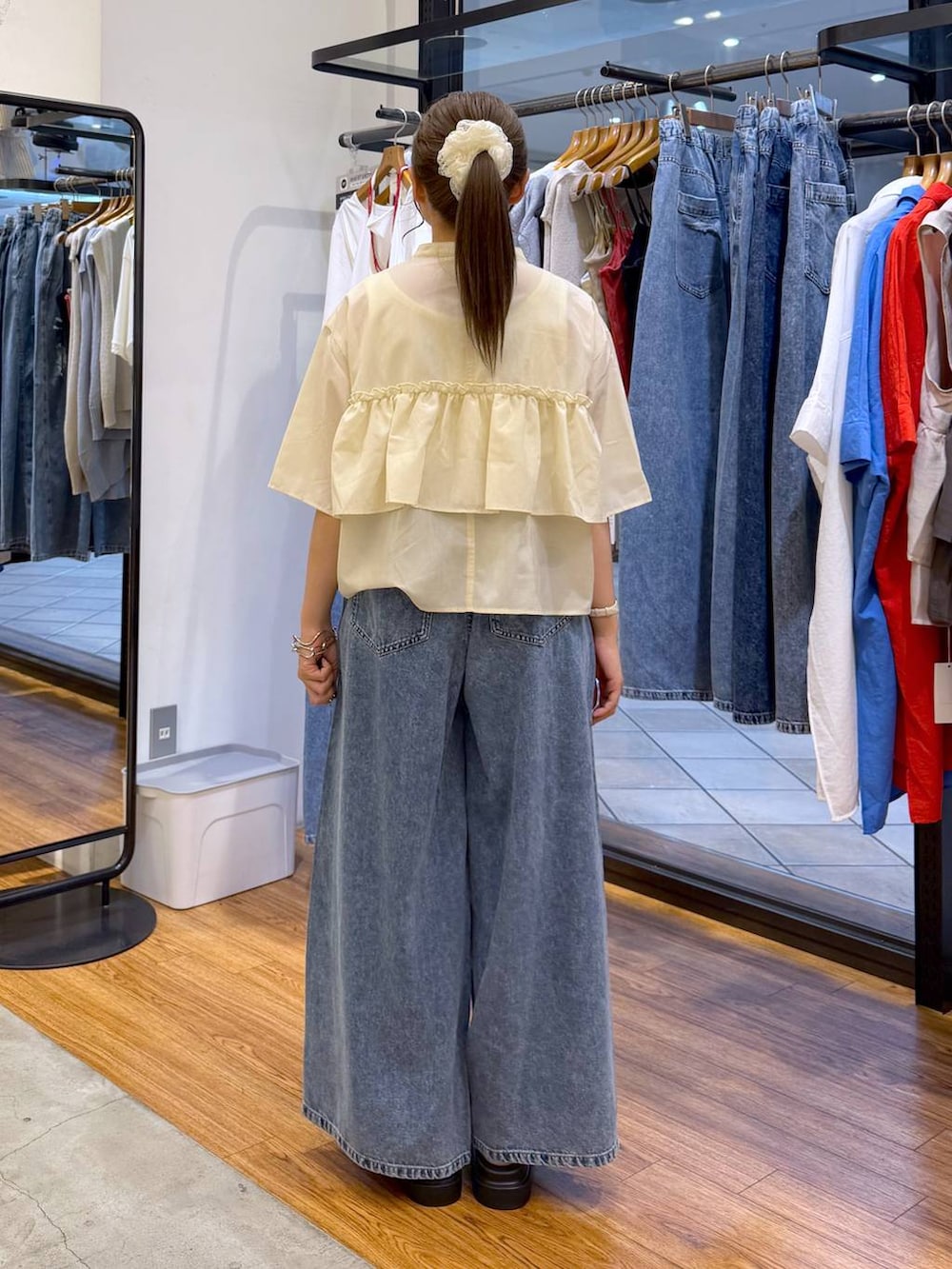 ブルー系のデニムパンツ、ホワイト系のサンダル、ブラウン系のショルダーバッグを着用したレディースの夏コーディネートの2枚目の写真