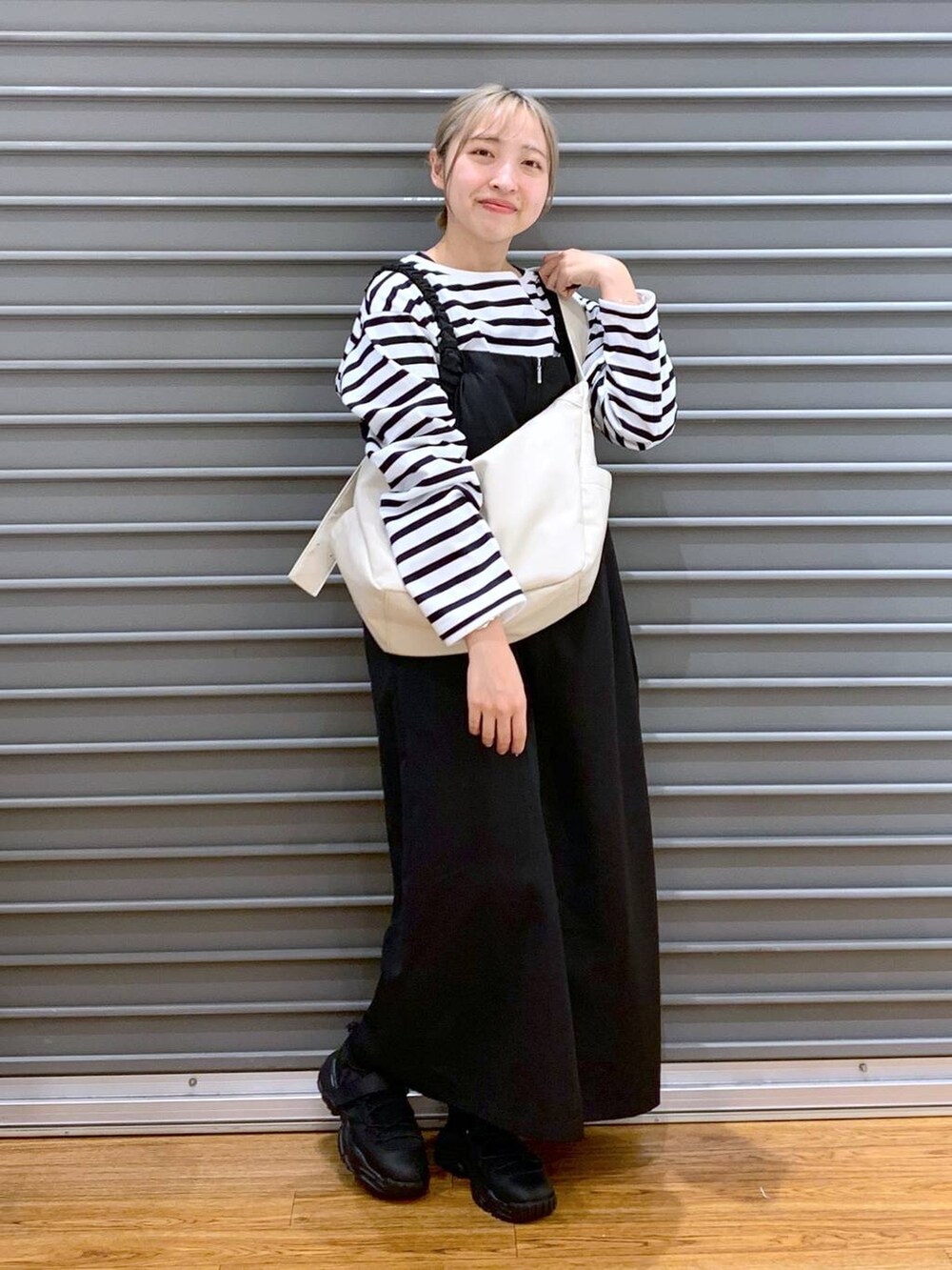 ブルー系のTシャツ/カットソー、ブラック系のスニーカー、ブラック系のジャンパースカートを着用したレディースの冬コーディネートの6枚目の写真