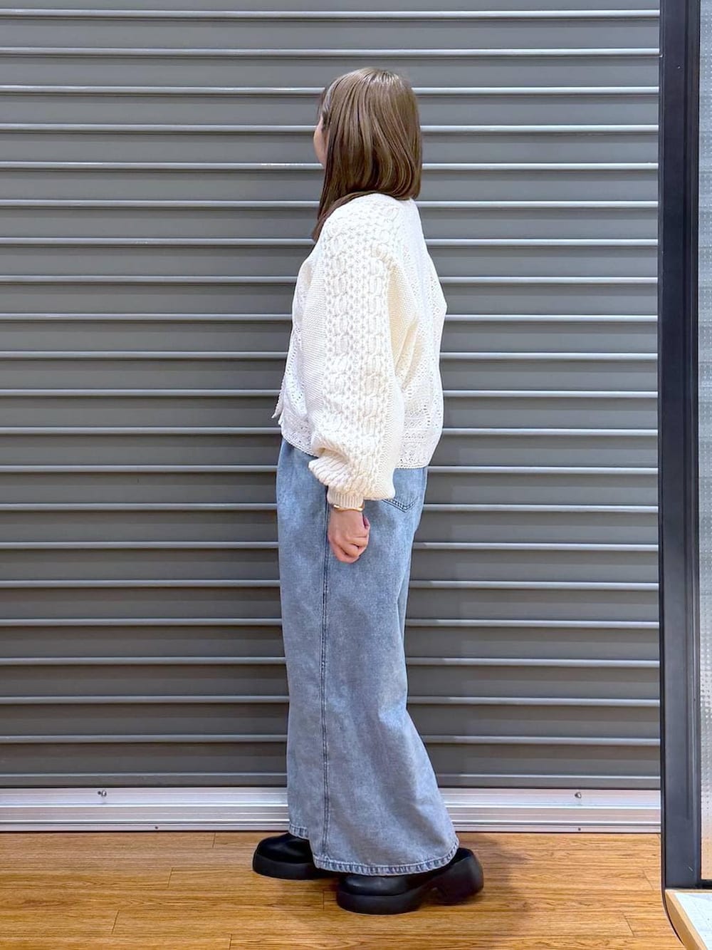 ブラック系のサンダル、ブルー系のデニムパンツ、ブラウン系のボストンバッグを着用したレディースの春コーディネートの3枚目の写真