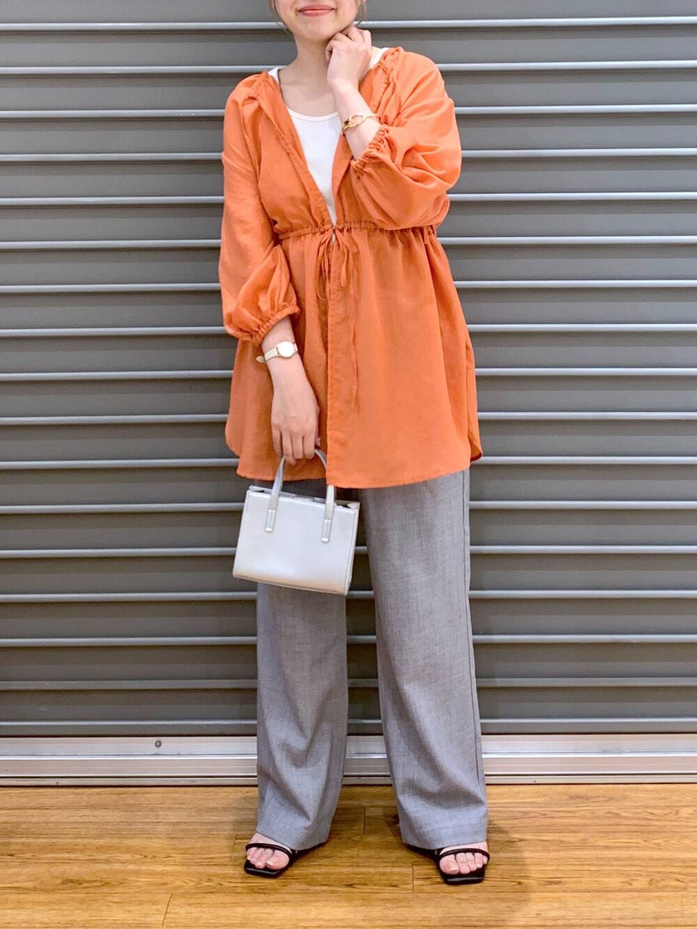 オレンジ系のシャツ/ブラウス、グレー系のショルダーバッグ、ブラック系のサンダルを着用したレディースの夏コーディネートの5枚目の写真