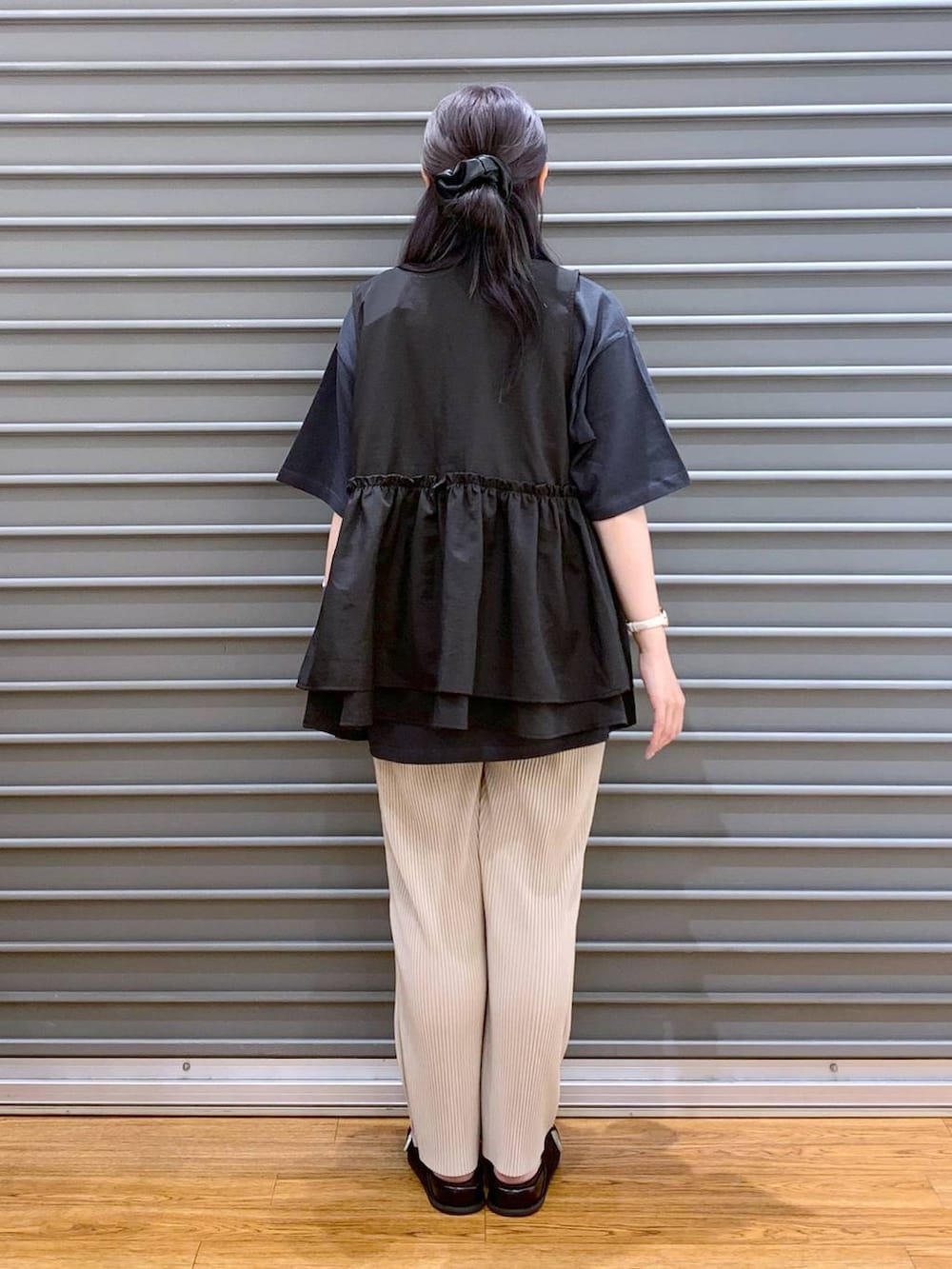 ブラック系のベスト、ベージュ系のその他パンツ、ブラック系のサンダルを着用したレディースの夏コーディネートの2枚目の写真