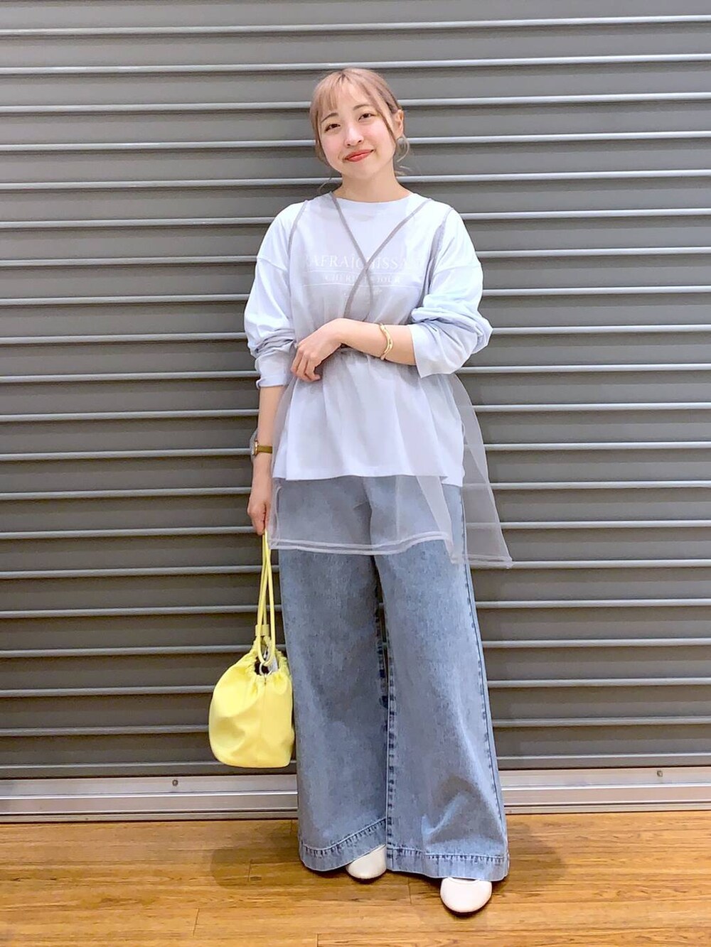 ブルー系のデニムパンツ、ホワイト系のバレエシューズ、イエロー系のショルダーバッグを着用したレディースの春コーディネートの3枚目の写真