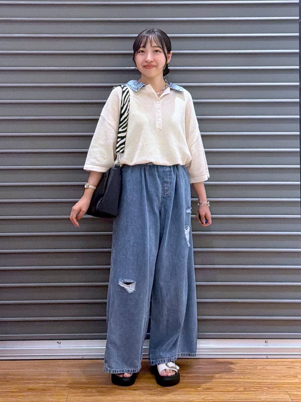 ブルー系のデニムパンツ、ホワイト系のサンダル、ブラック系のショルダーバッグを着用したレディースの夏コーディネートの4枚目の写真