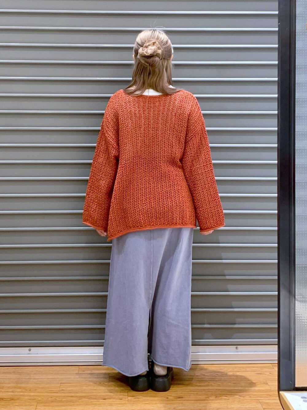 レッド系のニット/セーター、ブラック系のショルダーバッグ、ブラック系のサンダルを着用したレディースの春コーディネートの2枚目の写真