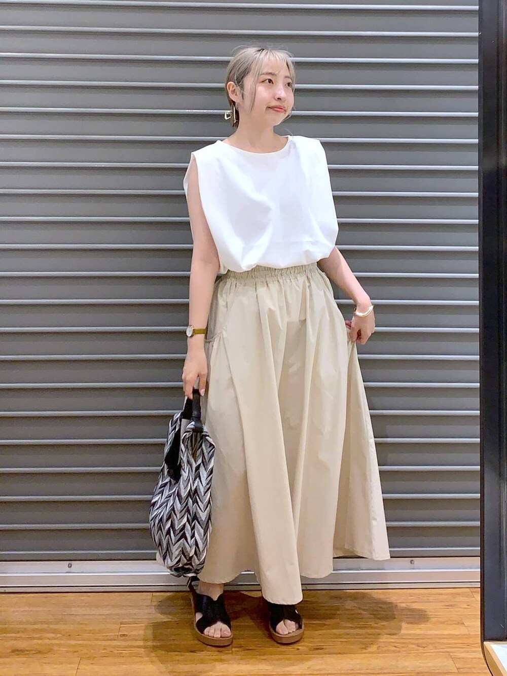 ブラック系のハンドバッグ、ホワイト系のスカート、ブラック系のサンダルを着用したレディースの夏コーディネートの3枚目の写真