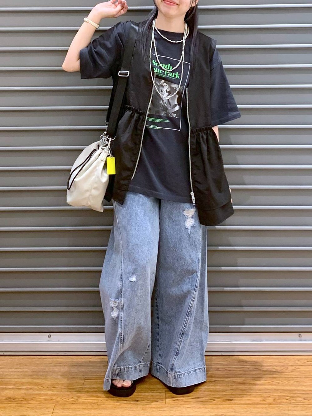 シルバー系のサンダル、ブルー系のデニムパンツ、ブラック系のベストを着用したレディースの夏コーディネートの4枚目の写真