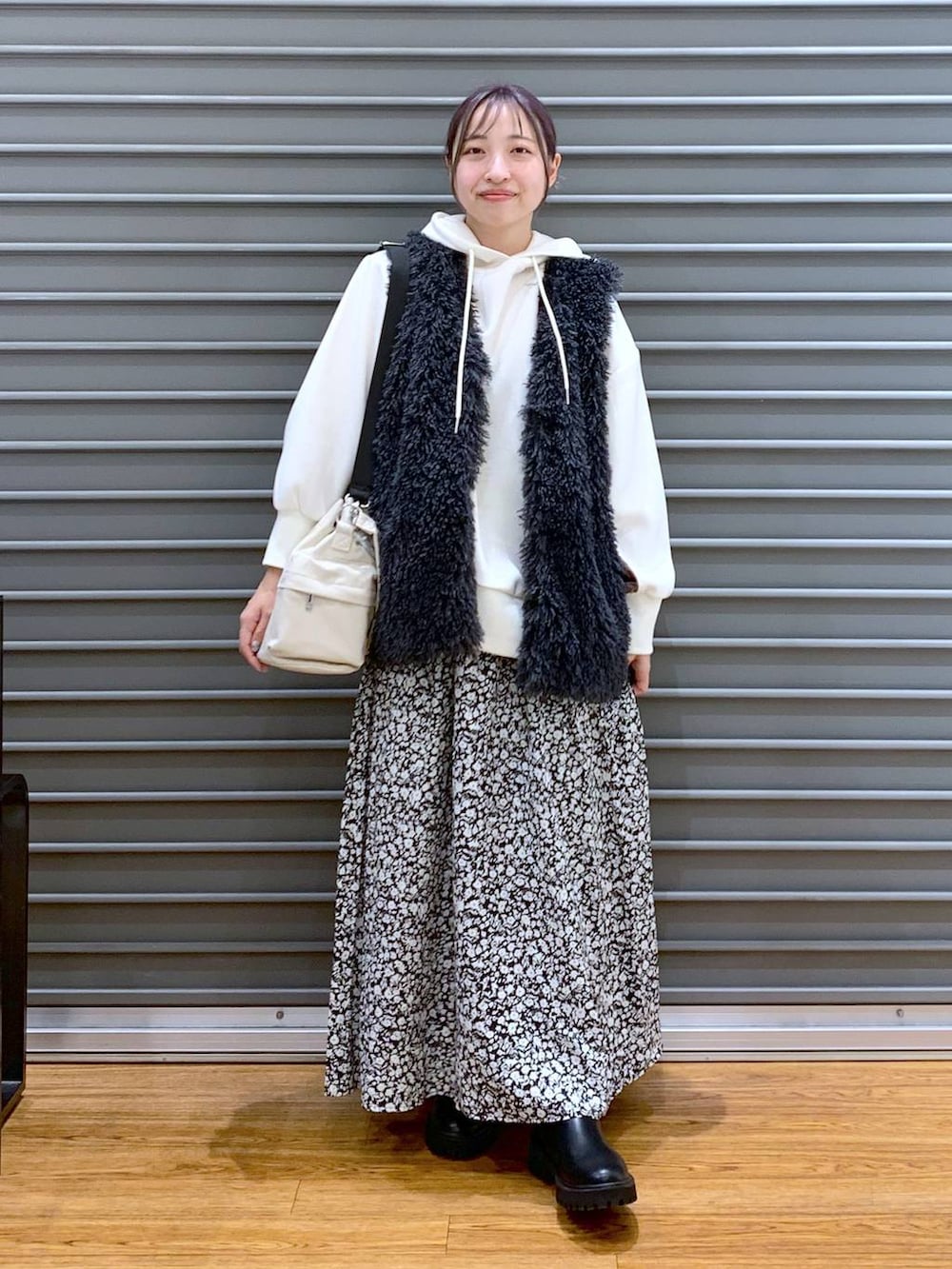 ブラック系のブーツ、ホワイト系のショルダーバッグ、ホワイト系のパーカーを着用したレディースの秋コーディネートの5枚目の写真