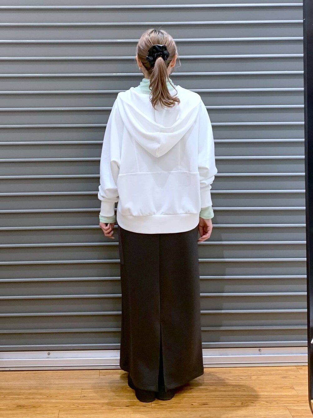 ブラック系のブーツ、シルバー系のショルダーバッグ、グレー系のスカートを着用したレディースの冬コーディネートの2枚目の写真