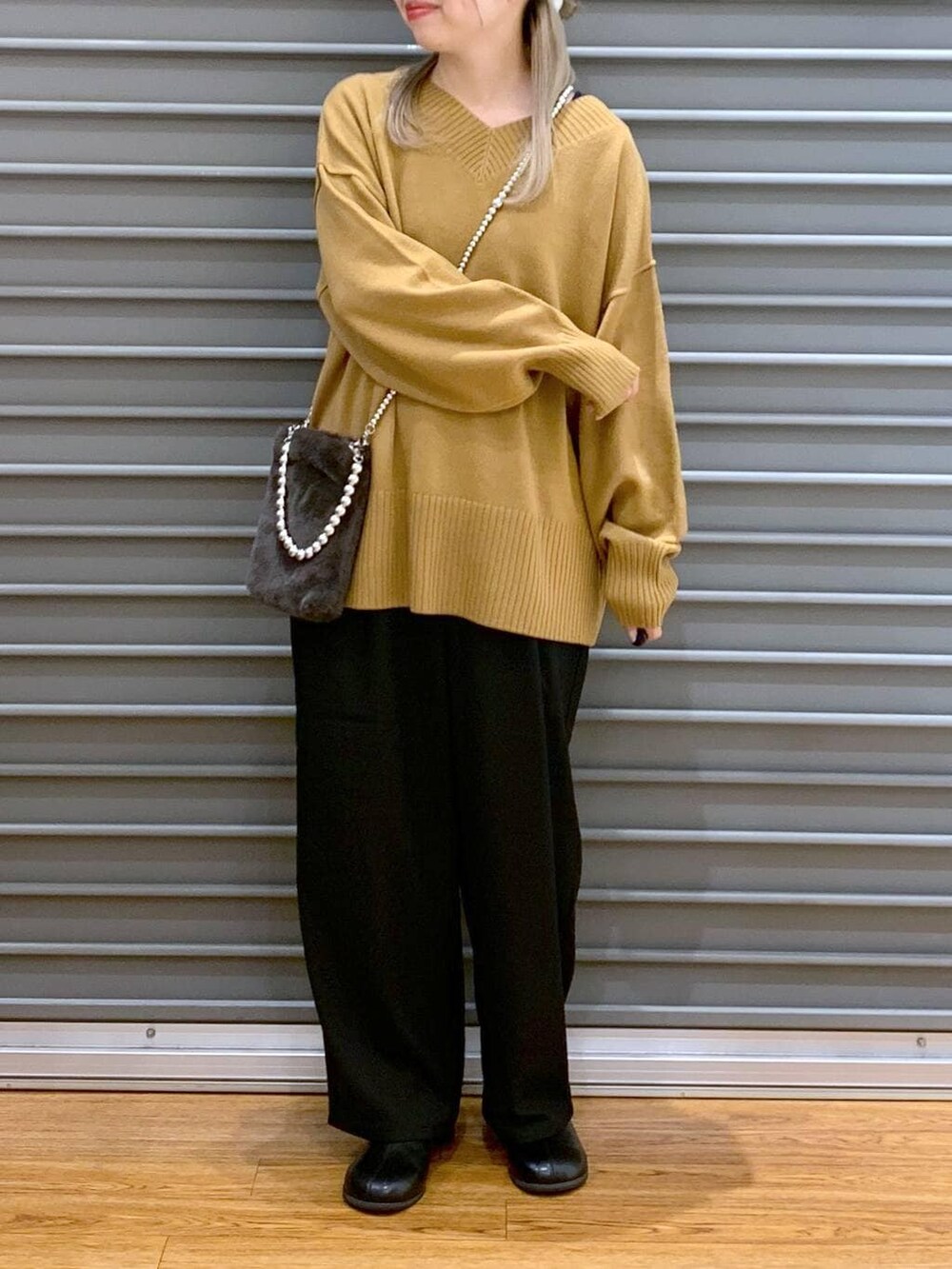 イエロー系のニット/セーター、ブラック系のその他パンツ、グレー系のショルダーバッグを着用したレディースの冬コーディネートの4枚目の写真