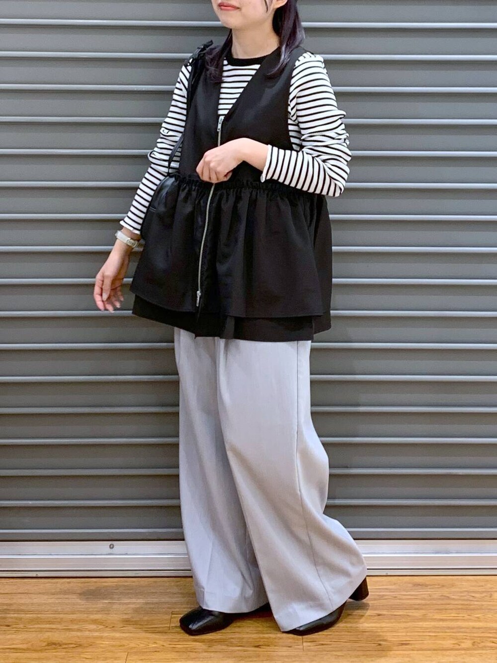 ブラック系のショルダーバッグ、ブラック系のパンプス、ブラック系のベストを着用したレディースの春コーディネートの4枚目の写真