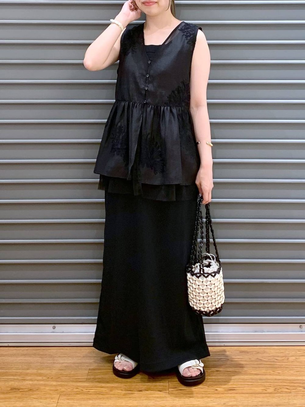 ホワイト系のサンダル、ホワイト系のハンドバッグ、ブラック系のシャツ/ブラウスを着用したレディースの夏コーディネートの5枚目の写真