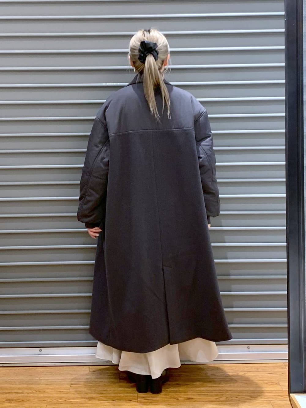 ブラック系のショルダーバッグ、ホワイト系のニット/セーター、ブラック系のブーツを着用したレディースの冬コーディネートの2枚目の写真