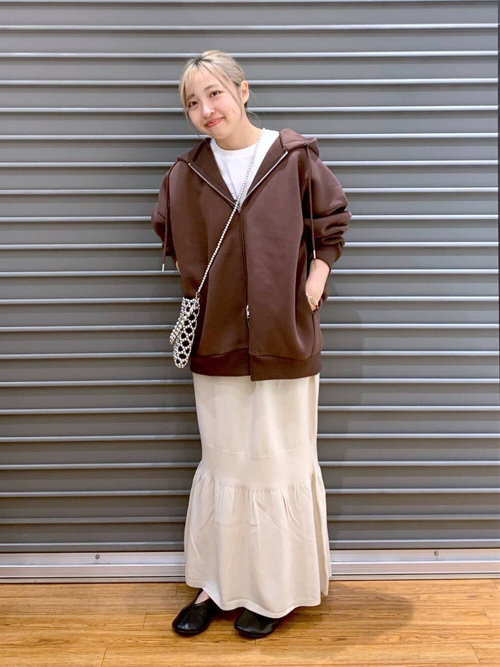 シルバー系のショルダーバッグ、ホワイト系のスカート、ブラウン系のパーカーを着用したレディースの秋コーディネートの4枚目の写真