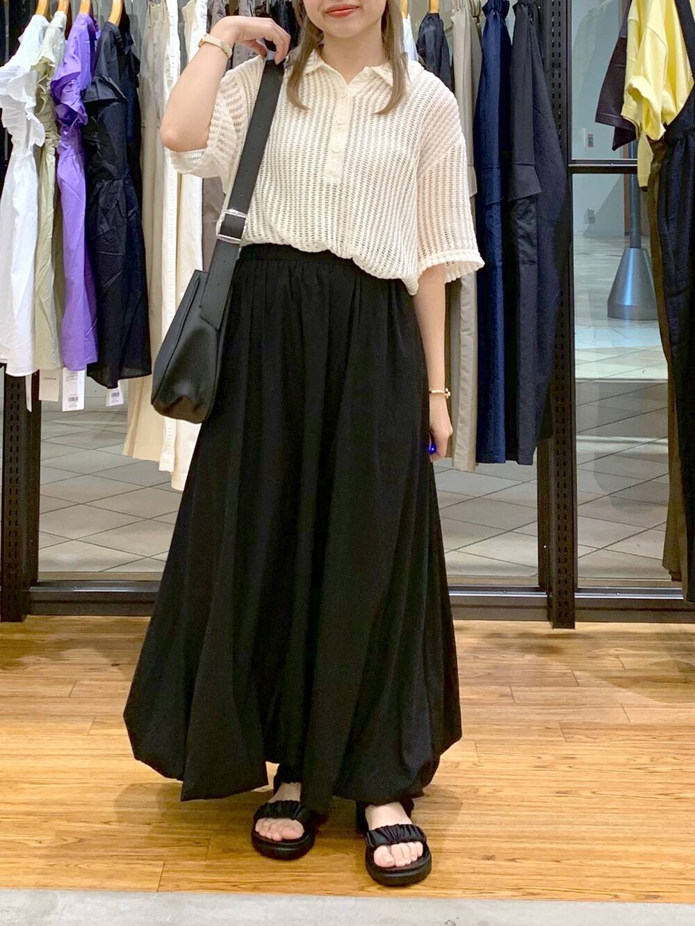 ブラック系のサンダル、ブラック系のスカート、ホワイト系のポロシャツを着用したレディースの夏コーディネートの5枚目の写真