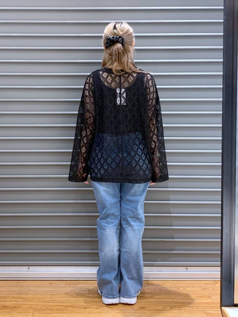 ブルー系のデニムパンツ、ブラック系のタンクトップ、シルバー系のスニーカーを着用したレディースの春コーディネートの2枚目の写真