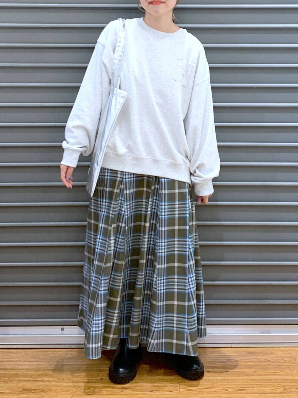 シルバー系のトートバッグ、ブラック系のブーツ、グリーン系のスカートを着用したレディースの冬コーディネートの4枚目の写真