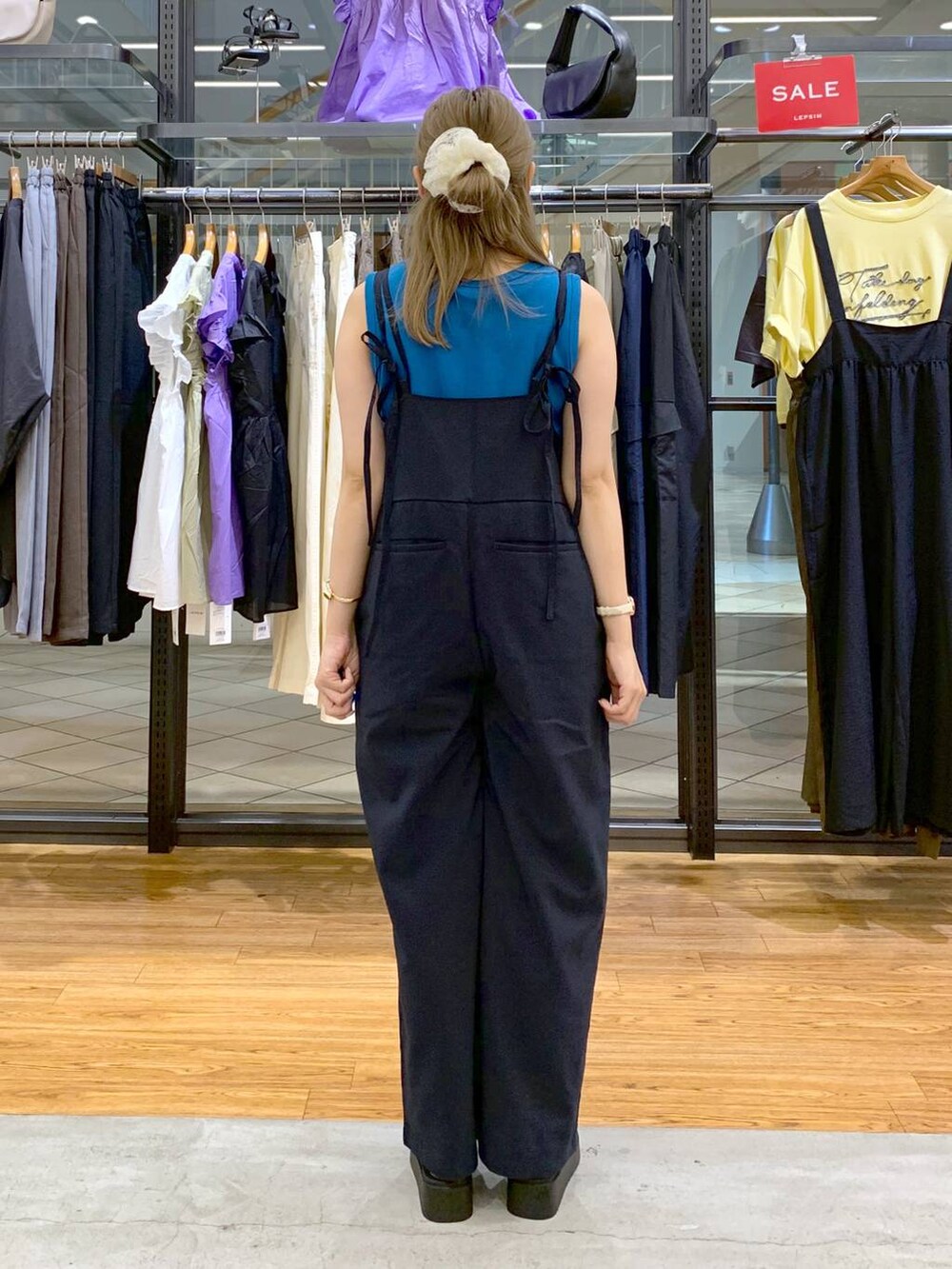 ブルー系のタンクトップ、シルバー系のサンダル、ブラック系のショルダーバッグを着用したレディースの秋コーディネートの2枚目の写真