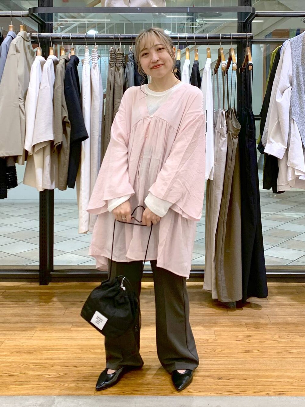 ホワイト系のTシャツ/カットソー、グレー系のスラックス、ブラック系のショルダーバッグを着用したレディースの春コーディネートの4枚目の写真