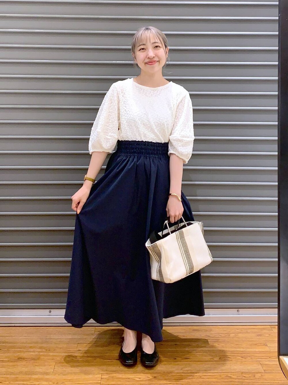 ホワイト系のショルダーバッグ、ブラック系のパンプス、ブルー系のスカートを着用したレディースの春コーディネートの3枚目の写真