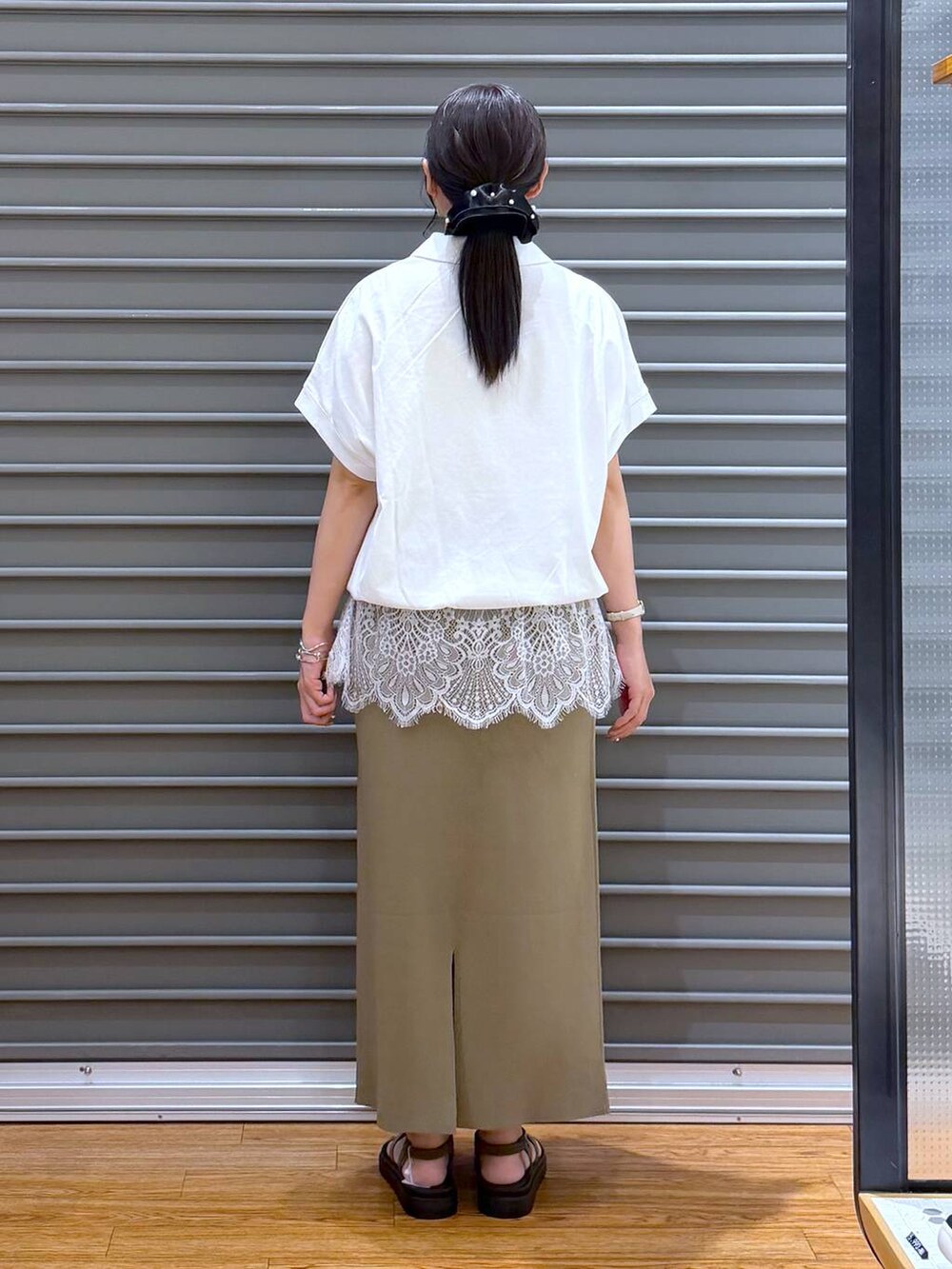 グリーン系のスカート、ブラウン系のサンダル、ホワイト系のTシャツ/カットソーを着用したレディースの夏コーディネートの2枚目の写真