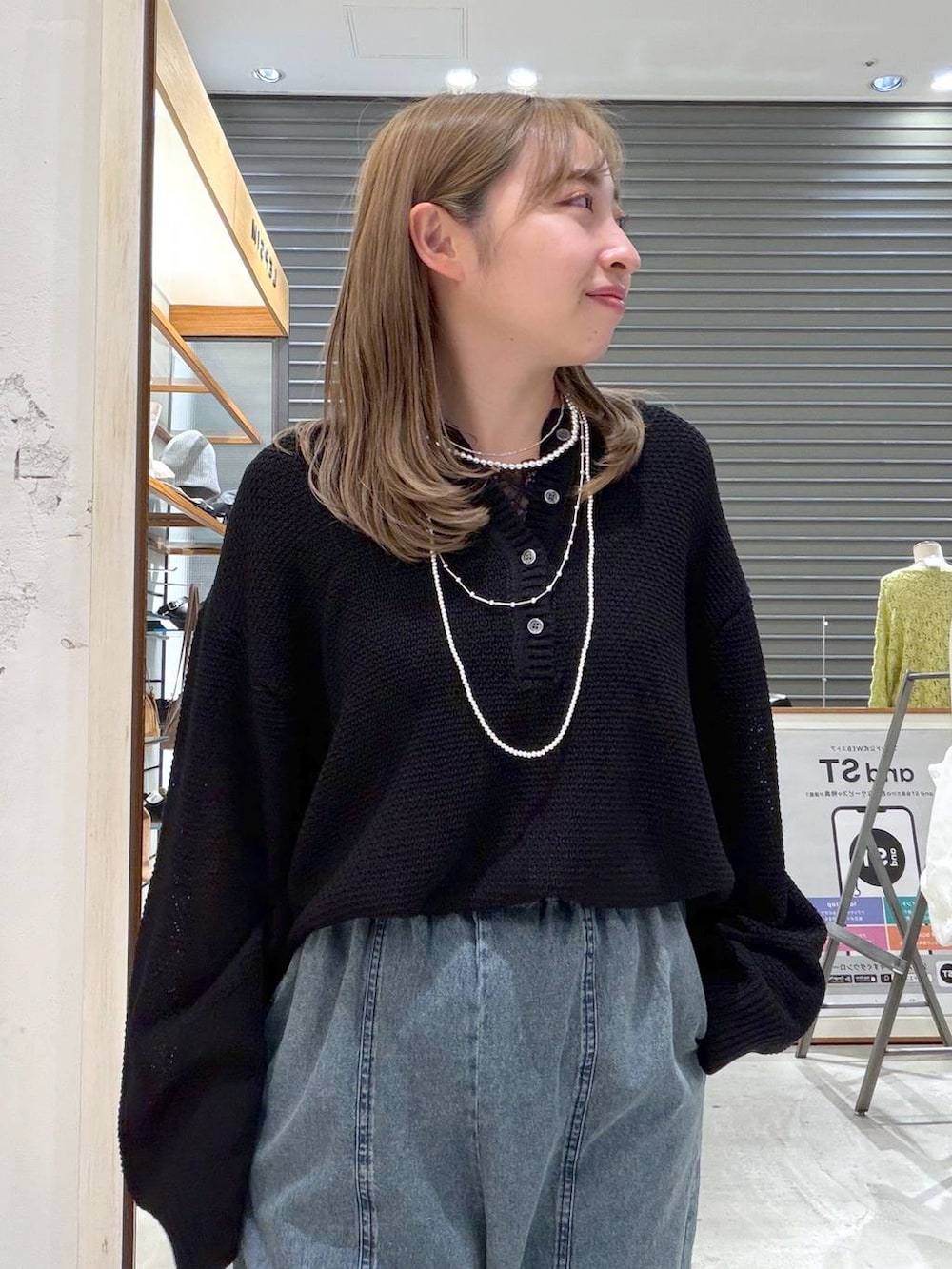 ブラック系のニット/セーター、ブルー系のデニムパンツ、シルバー系のネックレスを着用したレディースの春コーディネートの5枚目の写真