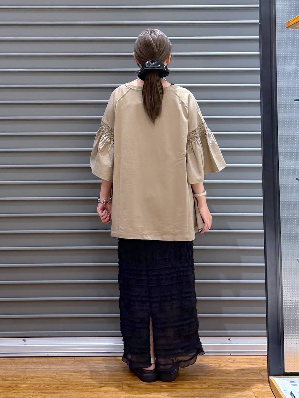 ベージュ系のTシャツ/カットソー、ホワイト系のサンダル、ブラック系のショルダーバッグを着用したレディースの夏コーディネートの2枚目の写真