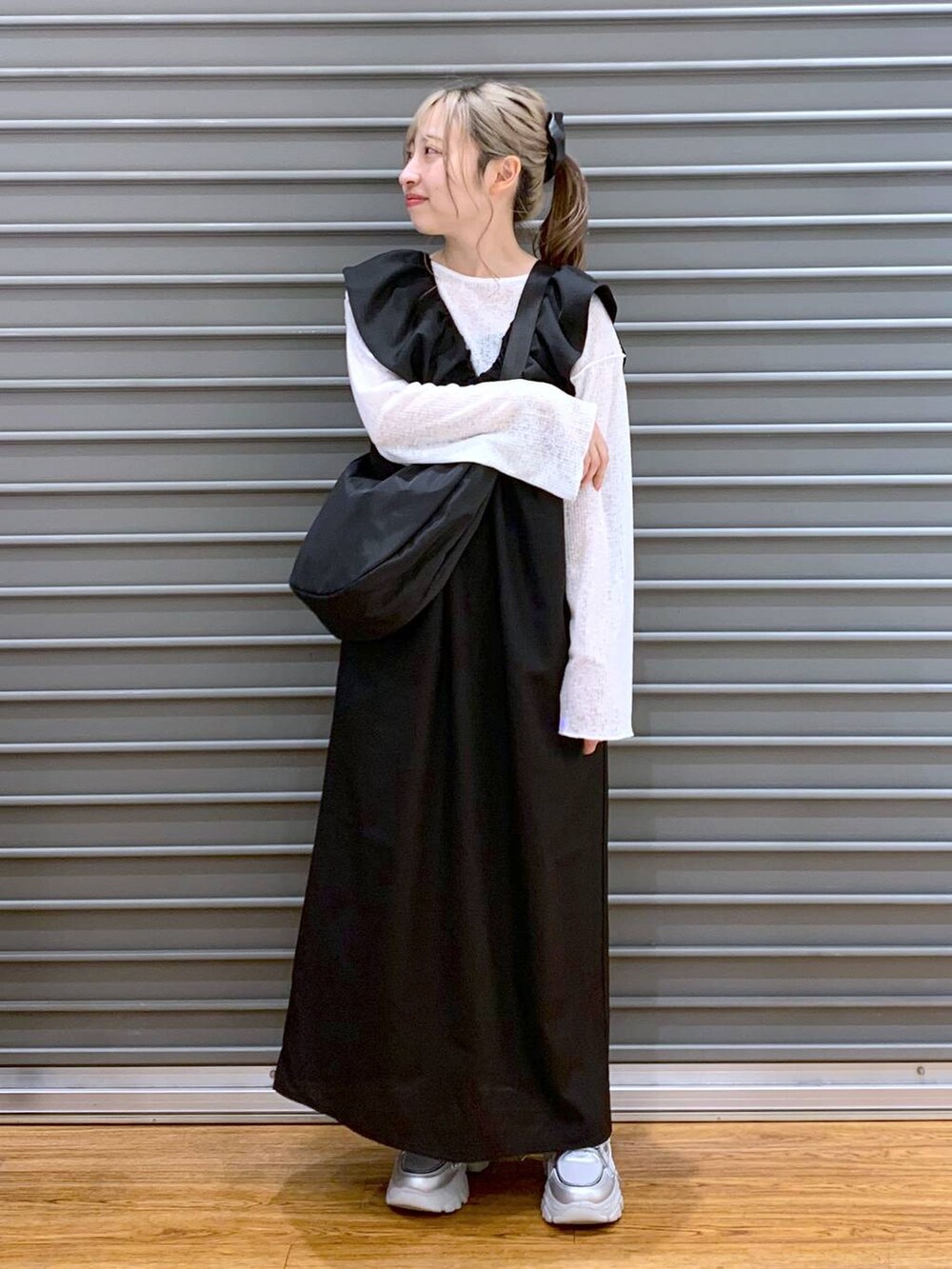 ブラック系のジャンパースカート、シルバー系のスニーカー、ホワイト系のTシャツ/カットソーを着用したレディースの春コーディネートの5枚目の写真