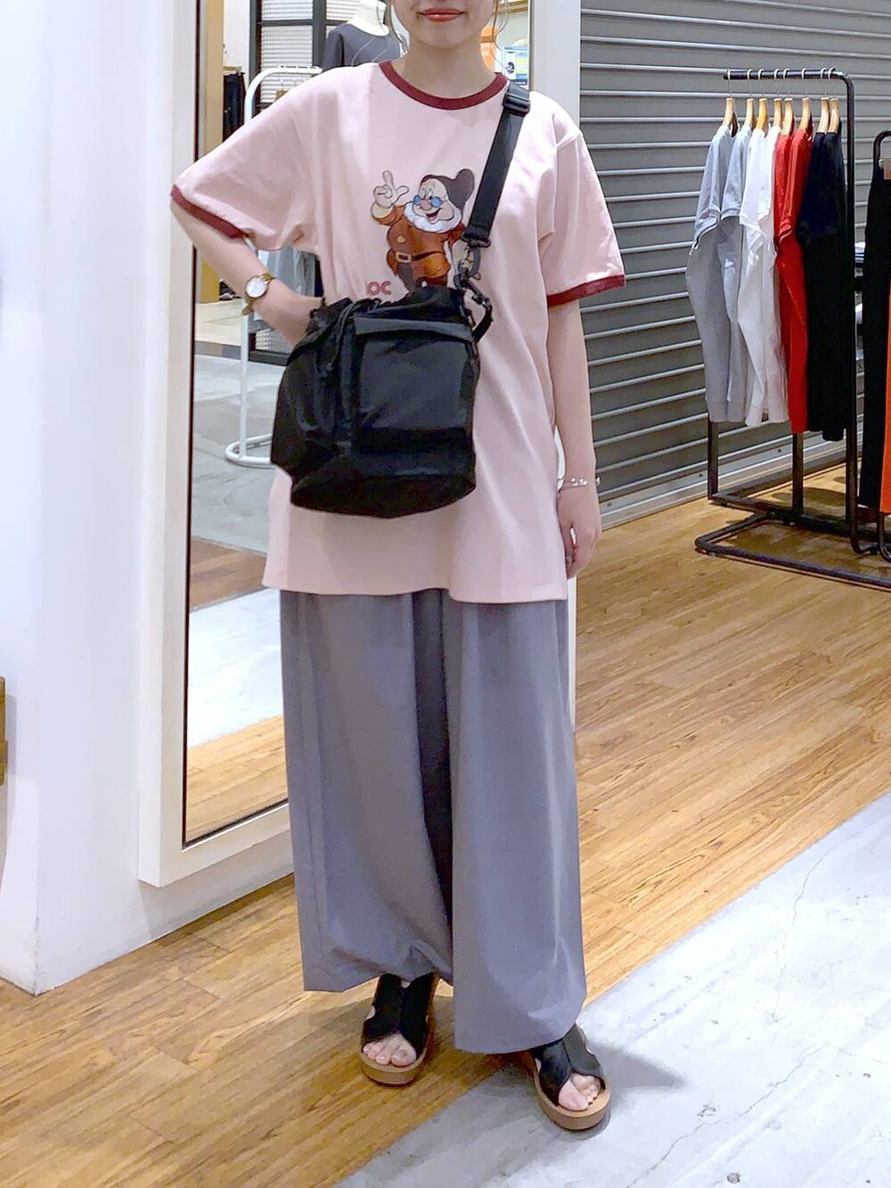 ブラック系のショルダーバッグ、ブラック系のサンダル、グレー系のスラックスを着用したレディースの夏コーディネートの2枚目の写真