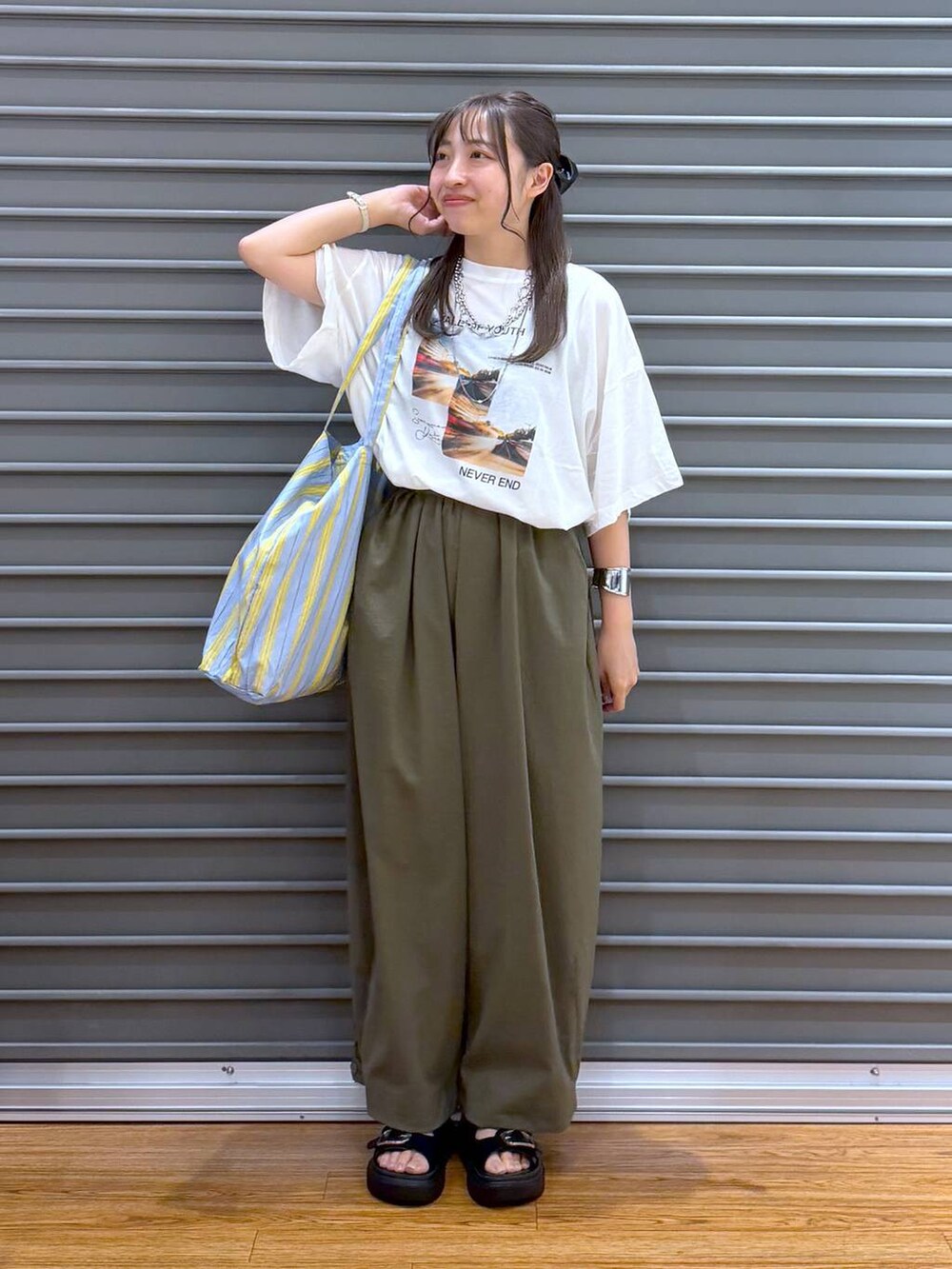ブルー系のトートバッグ、ホワイト系のTシャツ/カットソー、ブラック系のサンダルを着用したレディースの夏コーディネートの4枚目の写真