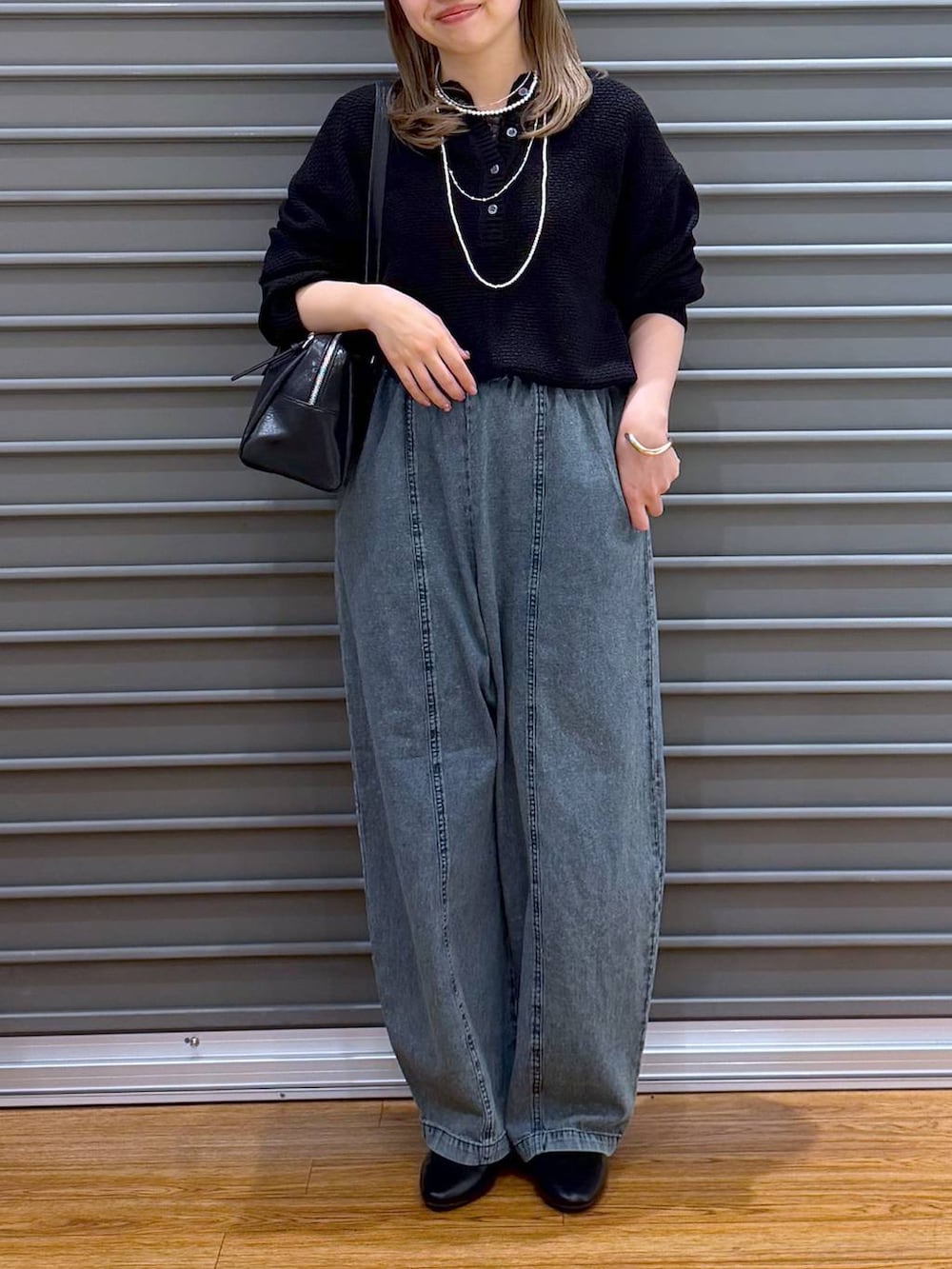 ブラック系のボストンバッグ、ブラック系のパンプス、ブルー系のデニムパンツを着用したレディースの春コーディネートの4枚目の写真