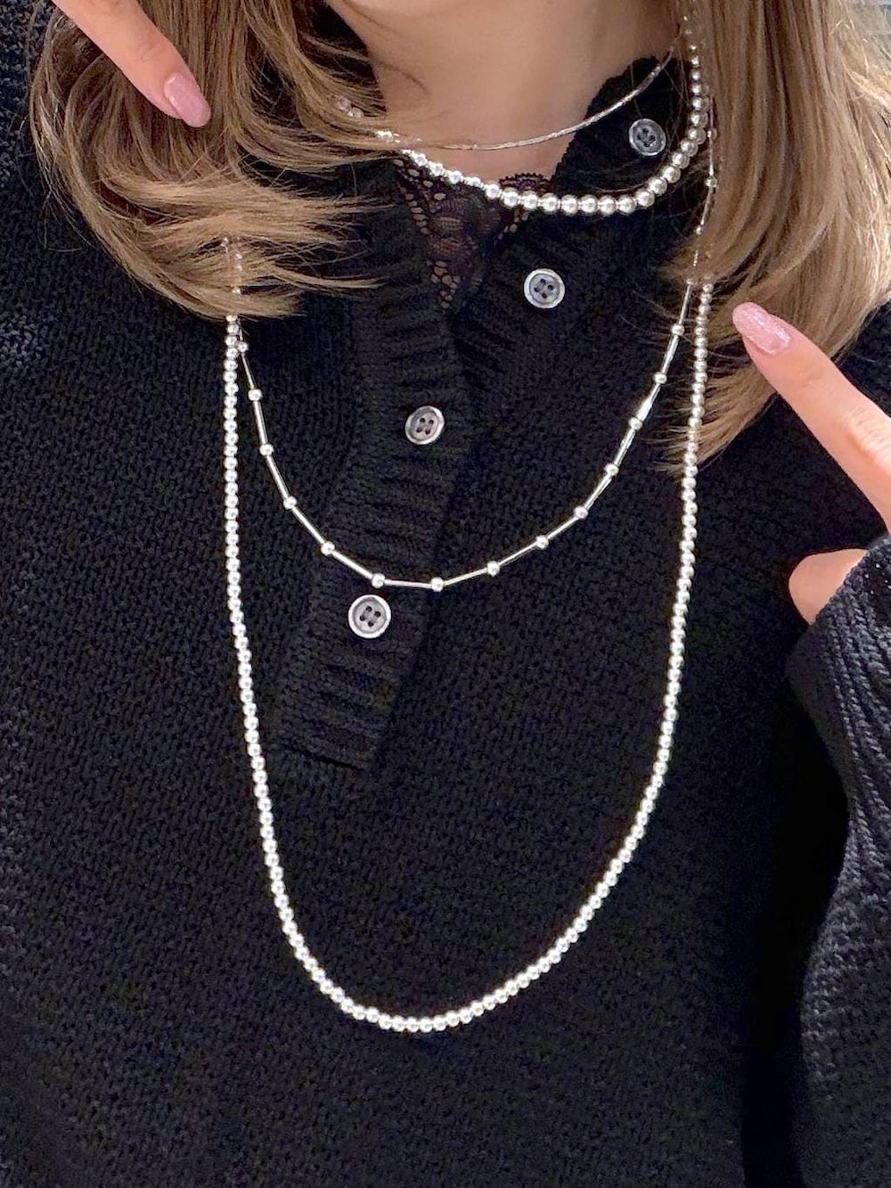 ブラック系のニット/セーター、ブルー系のデニムパンツ、シルバー系のネックレスを着用したレディースの春コーディネートの4枚目の写真