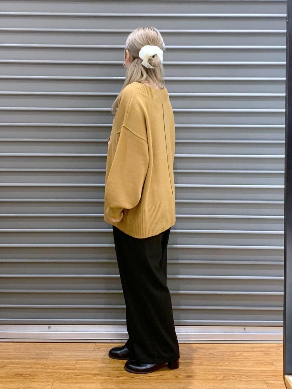 イエロー系のニット/セーター、ブラック系のその他パンツ、グレー系のショルダーバッグを着用したレディースの冬コーディネートの3枚目の写真