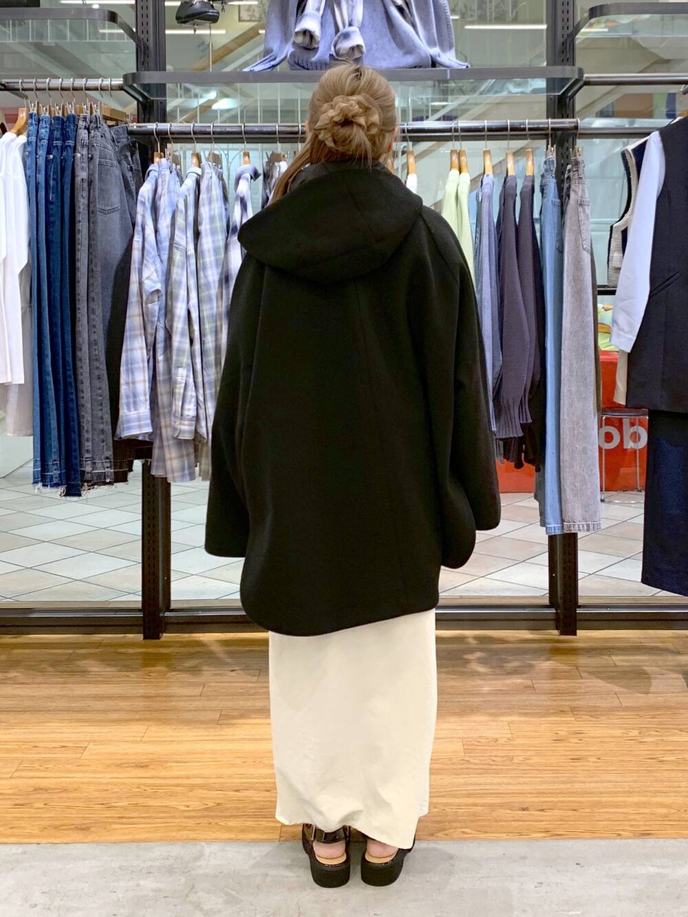 ブラック系のポンチョ、ホワイト系のスカート、ブラック系のショルダーバッグを着用したレディースの冬コーディネートの2枚目の写真