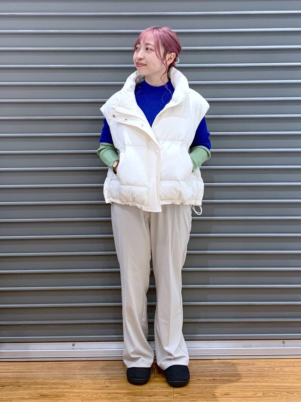 ブラック系のショルダーバッグ、ブルー系のニット/セーター、ホワイト系のダウンベストを着用したレディースの秋コーディネートの6枚目の写真