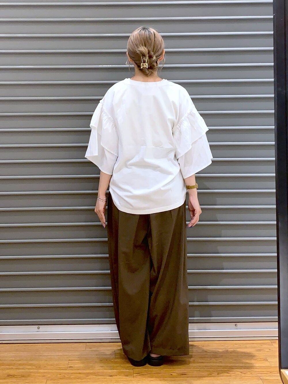 ホワイト系のショルダーバッグ、ブラック系のサンダル、ブラウン系のスラックスを着用したレディースの夏コーディネートの2枚目の写真