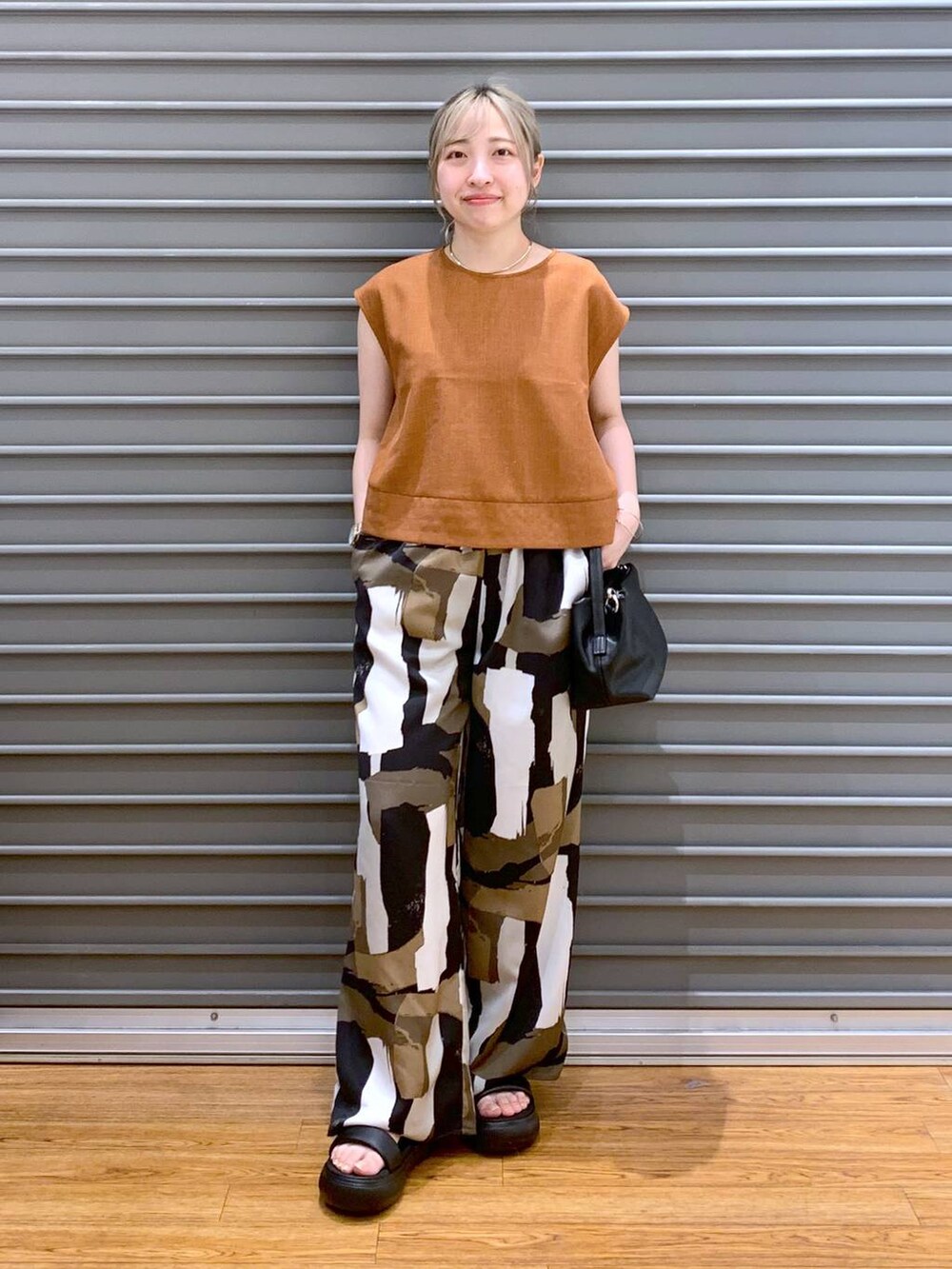 ブラック系のサンダル、オレンジ系のシャツ/ブラウス、ブラック系のショルダーバッグを着用したレディースの夏コーディネートの4枚目の写真