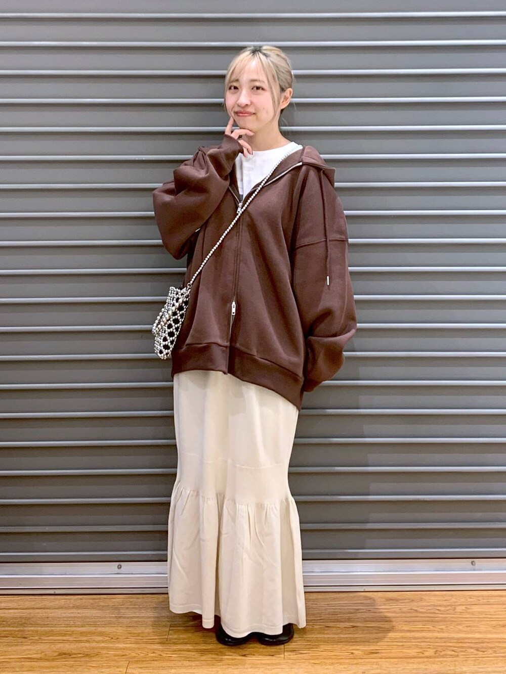 シルバー系のショルダーバッグ、ホワイト系のスカート、ブラウン系のパーカーを着用したレディースの秋コーディネートの7枚目の写真